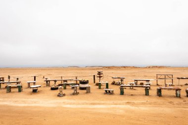 Namib-Naukluft Ulusal Parkı ve Namibya Sandviç Limanı yolu boyunca uzanan ahşap tezgahlarda sergilenen pembe tuz, bir çöl manzarasına karşıdır..