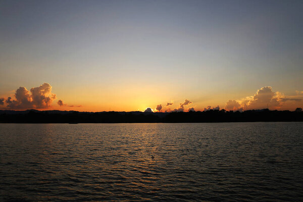 sunset in the evening over hill and lake.