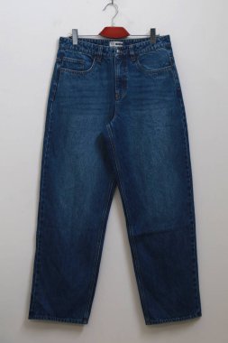 Pantolon askısı duvarda asılı. Duvarda asılı farklı renkte kot pantolon. Fabrika örnek kot pantolonu farklı yıkanmış.