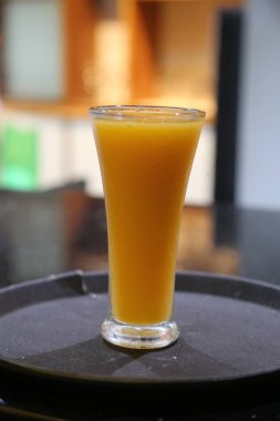 Ahşap bir masada bir bardak sarı mango suyu. Bir bardak mango kokteyli..
