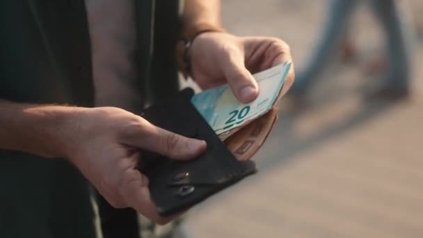 財布の中にお金を数える若い大人の男性の手のクローズアップビューの費用と収入を分析します 混雑した通りに立ってユーロ紙幣を保持白人男性 財務の概念 — ストック動画