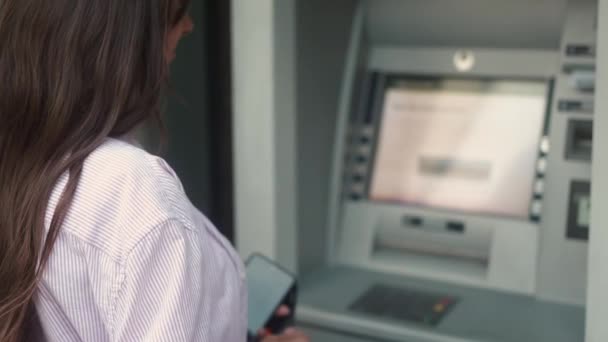 在街上用自动取款机取款机取款的年轻高加索女性的倒影 做银行交易的成年妇女持银行经营收据兑现现金 财务概念 — 图库视频影像