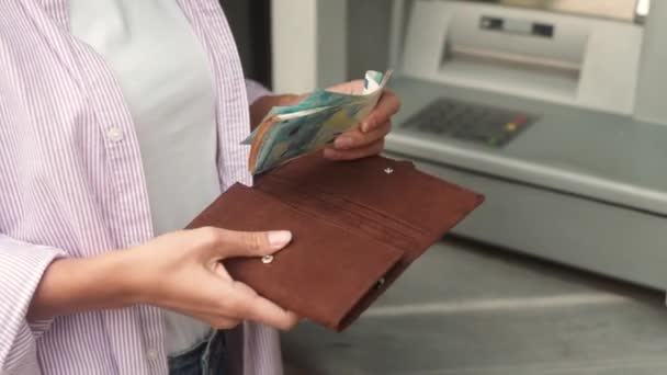 財布に引き出しお金を入れて若い大人の女性のクローズアップビュー 通りのAtmターミナルを使用して銀行カードからユーロ紙幣を受け取る白人女性 銀行口座のキャッシュアウト — ストック動画