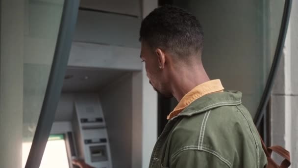 一个年轻的非裔美国人的侧面肖像用Atm终端按下进入针脚代码从银行卡取钱的按钮 具有吸引力的非洲男性在国外进行交易 — 图库视频影像