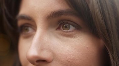 Extreme close-up of face of beautiful brown-eyed caucasian woman with nude makeup looking. Attractive pretty young adult female wearing perfect cosmetics thinking. Natural beauty concept.