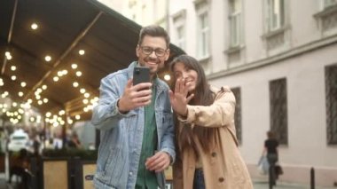Portrait of two young cute male and female friends video calling online using smartphone talking. Attractive happy man and beautiful pretty woman communicating using technologies.