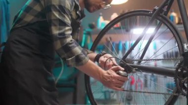 Skillful professional caucasian craftsman fixing and maintaining bike at authentic workshop with instruments using screwdriver. Attractive handsome male adjusting gears on bicycle.
