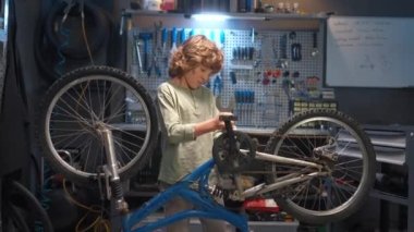 Garajda, kameraya gülümseyen aletlerle bisikleti tamir eden yetenekli çocuk portresi. Güzel bir çocuk, boş zamanlarını hobi yaparak harcayan mekanizmaları onarmayı öğreniyor..