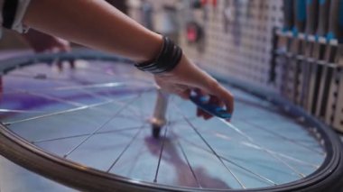Close-up view of beautiful hands of skillful hard-working female mechanic fixing bike wheel with wrench at modern workshop. Professional caucasian female worker repairing bicycles with tools.