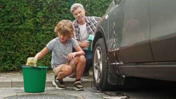 귀여운 뒷마당에 앉아서 아버지와 있습니다 머리의 남자는 아들에게 자동차 청소를 — 비디오