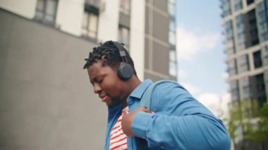 Sokakta yürürken kulaklık takan sakallı Afrikalı Amerikalı bir adam. Telefonunda müzik dinlerken sırt çantası taşıyan çekici bir erkek. Boş zaman. Dijital aygıtlar kullanarak eğlenmek.