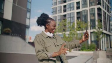 Sevimli Afrikalı Amerikalı kadın arkadaşlarıyla iletişim kurarken onları cep telefonundan arıyor. El sallıyor ve telefon kamerasında gülümsüyor. Çevrimiçi konuşma. Video çağrısı.