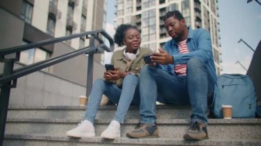 Merdivenlerde oturan ve sosyal verileri paylaşan iki Afrikalı Amerikalı meslektaşım. Güzel bir kadına kişisel hesabını internette gösteriyor. Ekranda gördüklerinden bahsediyorlar. Şehrin ortasında dinleniyor..