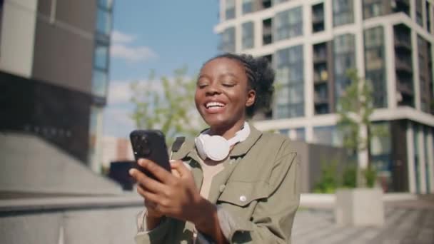 Güneşli Bir Günde Sokakta Yürürken Kulaklık Takan Mutlu Afrikalı Amerikalı — Stok video