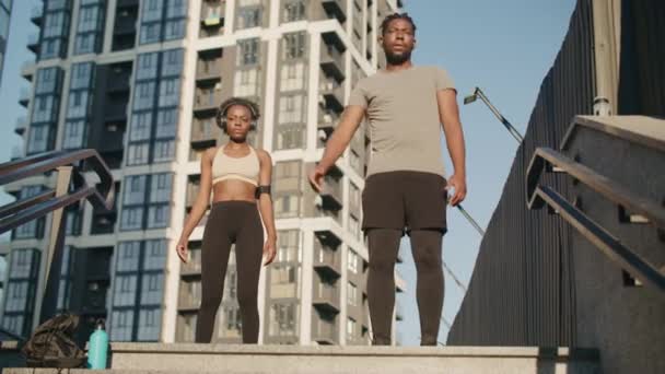 非裔美国人同事一起在户外工作 女人们在她的私人教练外出后继续锻炼 在城市的楼梯顶上完成了热身改善健康的概念 — 图库视频影像