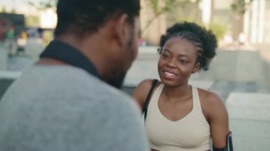 Caddenin ortasında birbirleriyle konuşan Afrikalı Amerikalı arkadaşlar. Erkeğe odaklanmış bir kadın dinliyor. Erkek, ek el hareketleriyle aktif olarak bir şeyi tarif ediyor. Ona gülümseyen bir kadın..