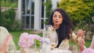 Moda modasına uygun, şık, güzel kadınların yaz günü kadeh kaldırarak kadeh kaldırdığı bir yer. Karışık ırklar mutlu genç erkekler ve kadınlar parti masasında içki içip gülüyor ve kadeh kaldırıyorlar..