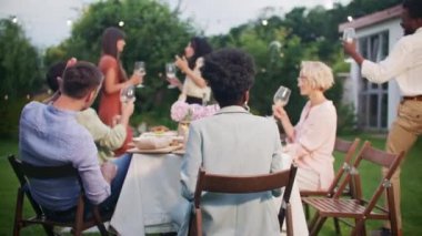 Öğle yemeğinde dışarıda yemekle masada oturan ve meyve suyu ve şarapla kadeh kaldıran mutlu çok ırklı şirket. Neşeli melez gençler akşam yemeği yiyip barbekü partisinde kadeh kaldırıyorlar. Hafta sonu kutlaması.