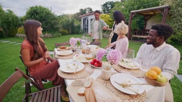 Eine Gruppe Verschiedener Freunde Sitzt Tisch Mit Essen Freien Begrüßt — Stockvideo