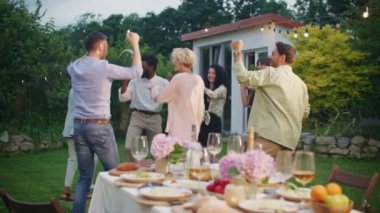 Çeşitli çok kültürlü arkadaşlar açık hava bahçe partisinde birlikte dans ediyorlar. Kutlama. Genç ve pozitif insanlar mükemmel bir yaz öğleden sonrasında eğleniyorlar. Arkadaşlık, boş zaman ve hafta sonları konsepti.