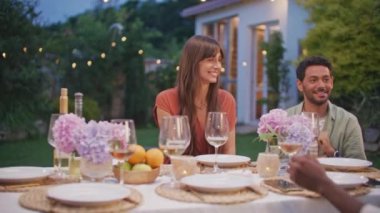 Kamera hareket ediyor. Neşeli, mutlu, dışarıda oturan, kameraya bakıp gülümseyen doğum günü partisini kutlayan güzel bir kadın. Arkadaşlık ve neşe kavramı - Kız yüzüne odaklan.