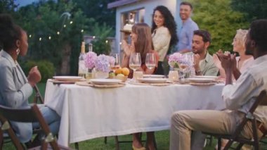 Çok kültürlü gençler, açık hava partisinde güzel bayanı doğum günüyle kutluyor. Doğum günü kızı mumları üflüyor ve dilek tutuyor. Doğum günü pastasında yanan mum. Arkadaşlar birlikte eğleniyor..