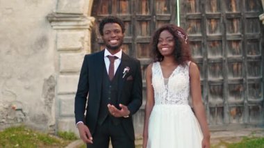 Tatmin olmuş genç Afrikalı Amerikalı çift alyanslarını kameraya gösteriyor. Çekici koca ve gelinlik giymiş güzel kadın düğün töreninden sonra neşeyle gülümsüyor. Yeni bir aile..