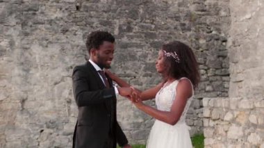 Güzel bir Afrikalı Amerikalı çift taş bina ya da kale yakınlarında romantik bir şekilde dans ediyor. Beyaz elbiseli güzel gelin sevgili erkeğiyle dans ediyor. Aile yaratmak. Düğün günü konsepti