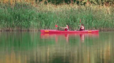 Güzel beyaz çift göl veya nehirde romantik vakit geçiriyorlar. Büyük kırmızı kanoda kürek çekerken doğanın tadını çıkarıyorum. Birbirimize ve doğaya yaklaşıyoruz. Rahatlatıcı hafta sonu.