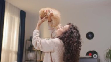 Sevimli beyaz kadın kırmızı kedisini elleriyle tutuyor. Kumral saçlı, evcil hayvanını kaldıran ve onunla oynayan güzel bir kadın. Olumlu gülümsüyor ve birlikte eğleniyoruz..
