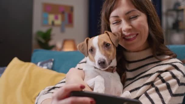 Όμορφη Καυκάσια Γυναίκα Αγκαλιάζει Υπέροχο Σκυλί Της Ενώ Χρησιμοποιώντας Smartphone — Αρχείο Βίντεο