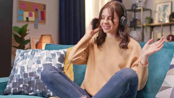Acercándose Positivamente Mujer Caucásica Con Auriculares Escuchando Música Cómodamente Sentado — Vídeo de stock