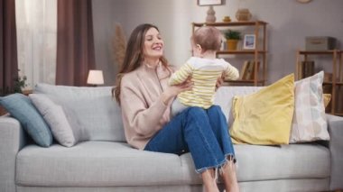 Anne kızını kustu. Anne ve bebek birlikte eğleniyorlar. Anne ve çocuk evde oynaşıyor. Çocuk oyunlarıyla oynayan bir kadın. Anne gıdıklayan kızı. Ebeveynlerin boş vakitleri.