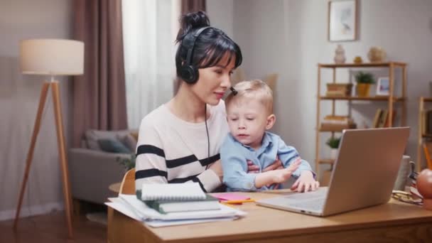 Menino Impedindo Mãe Trabalhar Mulher Usando Fones Ouvido Segurando Filho — Vídeo de Stock