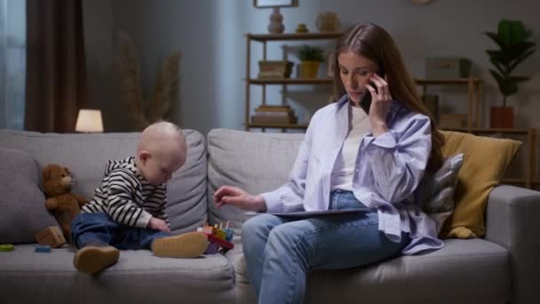 Γυναίκα Μιλάει Τηλεφωνικώς Και Φροντίζει Παιδί Μητέρα Κοιτάει Χαρτί Της — Αρχείο Βίντεο