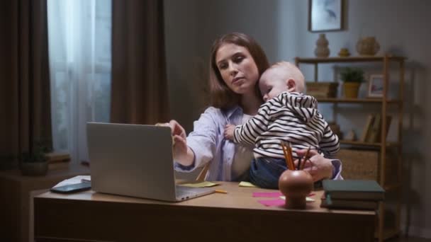 소년은 피곤하고 잠들어 노트북과 아기와 어깨에 누워있는 어머니는 노트를 만들고 — 비디오