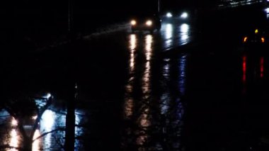 Cars drive on a night road in the rain. Cars on the night city highway. Reflection of car headlights on wet pavement. Cars are moving fast on the freeway. White and yellow auto lights on a dark road