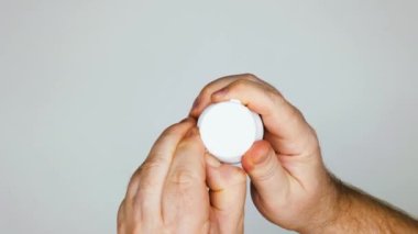 Hands open a vial of pills. Man pours pills from a pill vial into his palm. Plastic Medicine Pill Bottle with Cap for Prescription Medication. Medic Container Pharmaceutical Grade. Top view. Close-up