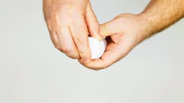 Pills are poured into the palm. Trembling male hands take out white pills from a medicinal vial. Isolated. Close-up. The patient of the clinic takes medication. Drugs in a plastic medical bottle.