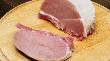 Meat spinning on a plate. A juicy piece of pork is shown from the best angles. Meat steak on the ribs on a wooden board. Delicate pink piece of meat. Beef fillet for cooking signature stack. Close-up