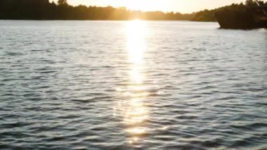 Sunny path on the river. The sun over the forest is reflected in the blue waves. Sunset on the river. Sunrise on the lake. Beautiful water landscape. Sea waves, forest shore and industrial ship