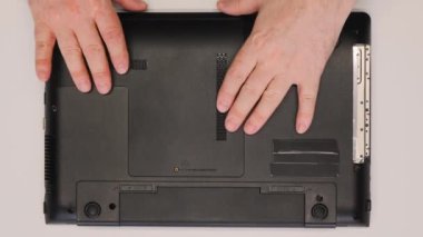 Usta laptopun kapağını açar. Atölyedeki bir tamirci tamir için bir dizüstü bilgisayarı söker. Servis atölyesinde bilgisayar ekipmanlarının bakımı. Yakın plan. Üst görünüm