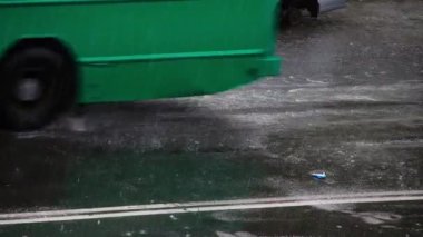 Yağmurda otoyolda tıbbi maske. Araba ve otobüslerin tekerlekleri altında yağmur damlaları arasında birikintideki kullanılmış tıbbi maske. Virüs salgını konsepti. Coronavirüs salgını. Tekerleklerin altından püskürt