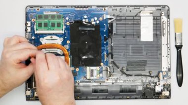 Tamirci, vantilatörü bilgisayardan söküyor. Yakın plan. Bir tamir teknisyeni bilgisayarı söker. Karmaşık elektronik tamiri. Bir atölyede ana kart, işlemci, mikroçip ve diğer bilgisayar parçaları