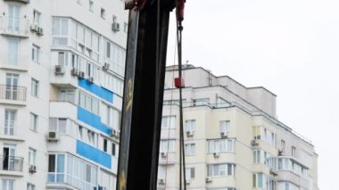 İnşaat alanında seyyar vinç var. Çelik kablo vinçli vinç yelkeni. Güçlü çelik kancalı vinç ve beton levhaları ve ağırlıkları kaldırmak için halatlar. Çok katlı binalar.