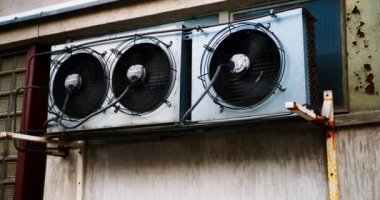 Klima vantilatörleri sokak duvarında dönüyor. Endüstriyel klimalar tam kapasite çalışıyor. Aşırı sıcakta özel iklim ekipmanları. Pervaneler hızlı dönüyor. Sistemi böl