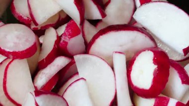 Dilimlenmiş sebze salatası. Vejetaryen salatası, turp, tuz, zeytinyağı. Sağlıklı yemek. Olgun kesilmiş sebze salatası çatalla karıştırılır. Çiftçilerin bahçesinden taze sebzeler. Yakın plan.