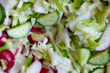 Sebze salatası karıştırıyorum. Vejetaryen salatası, salatalık, lahana, tuz, zeytinyağı. Sağlıklı yiyecekler. Olgun kesilmiş sebze salatası çatalla karıştırılır. Çiftçilerin bahçesinden taze sebzeler