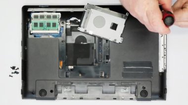 Bir dizüstü bilgisayarı söküyorum. Tamirci vidaları söker. Yakın plan. Bir tamir teknisyeni bilgisayarı söker. Karmaşık elektronik tamiri. Bir atölyede mikroçipler ve diğer bilgisayar parçaları