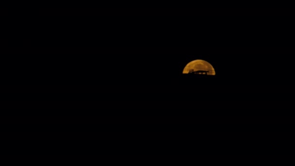 満月は家の裏から昇る 月は徐々に黒い空に降ります 星のない暗い空に差し迫った嵐の美しい月明かりの夜 月の家の後ろに隠れている 4K映像 — ストック動画
